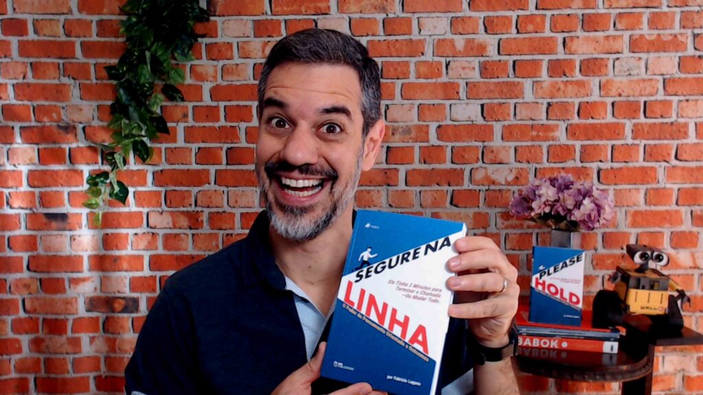 Fabrício Laguna segurando Segure na Linha com a versão em inglês ao fundo